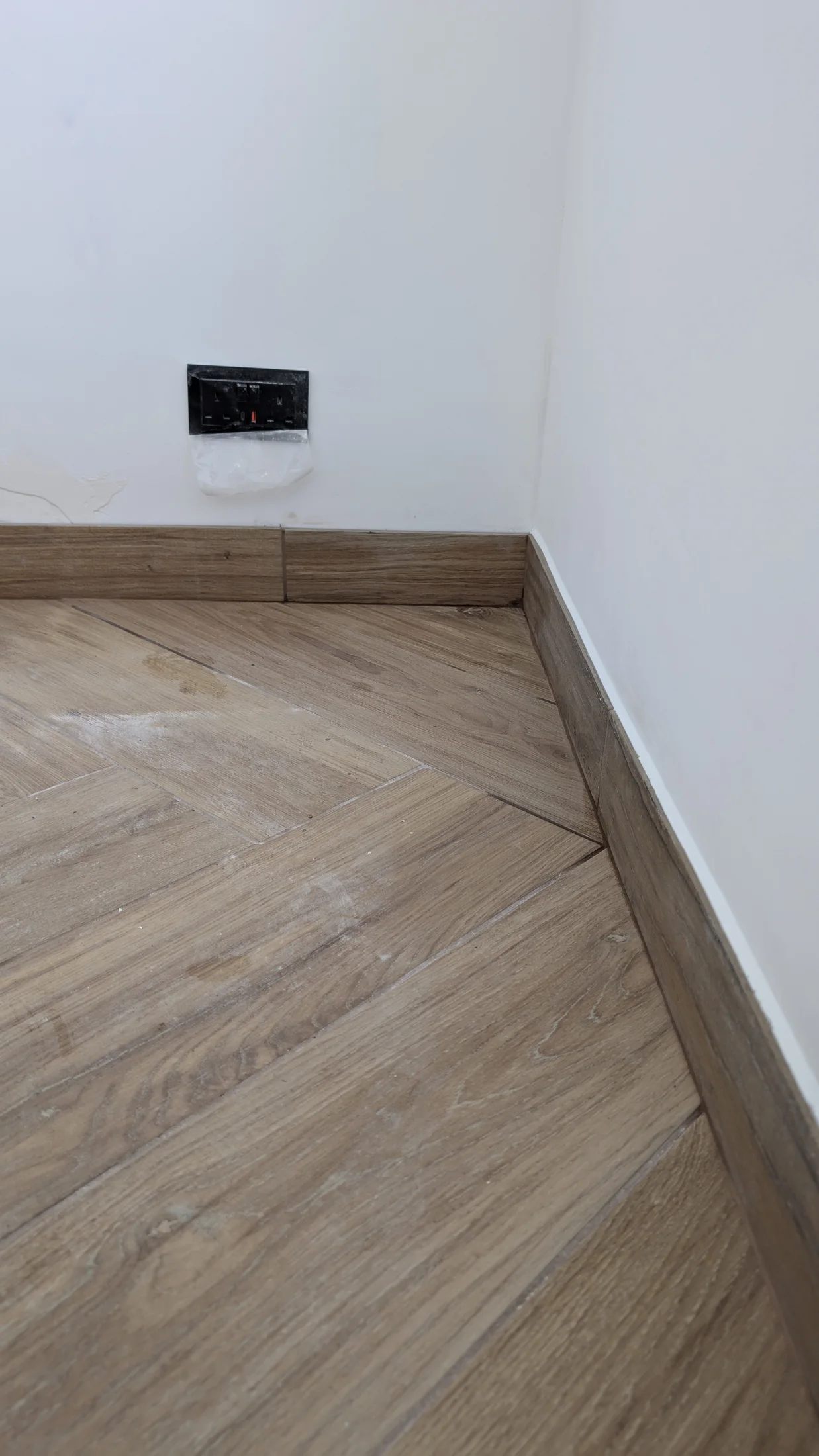 Finished floor tiles and skirting against the white interior wall