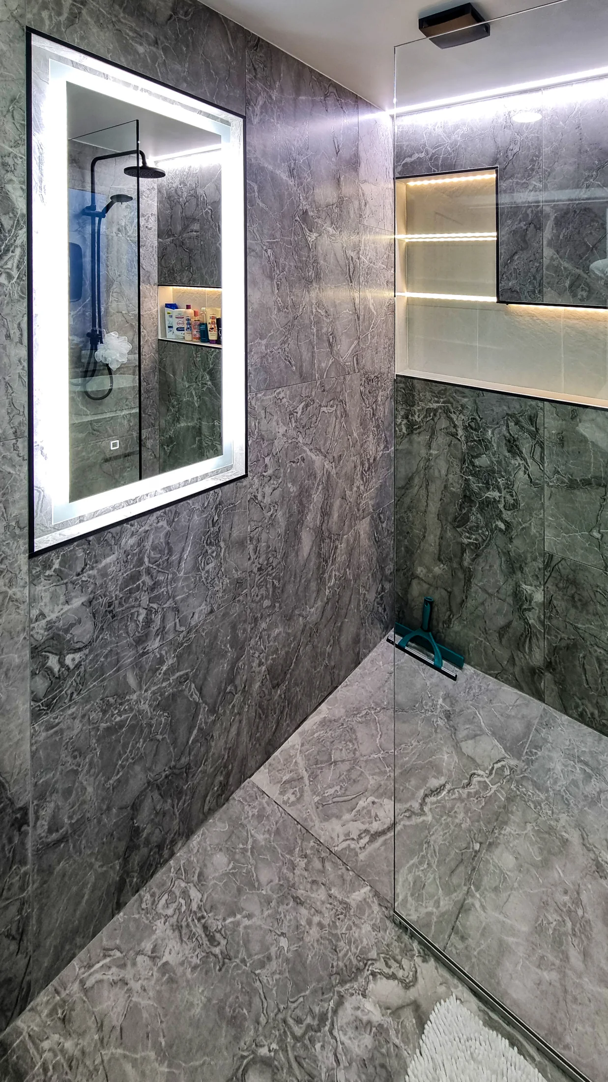 Backlit mirror and continuous illuminated shelf in the completed dark bathroom