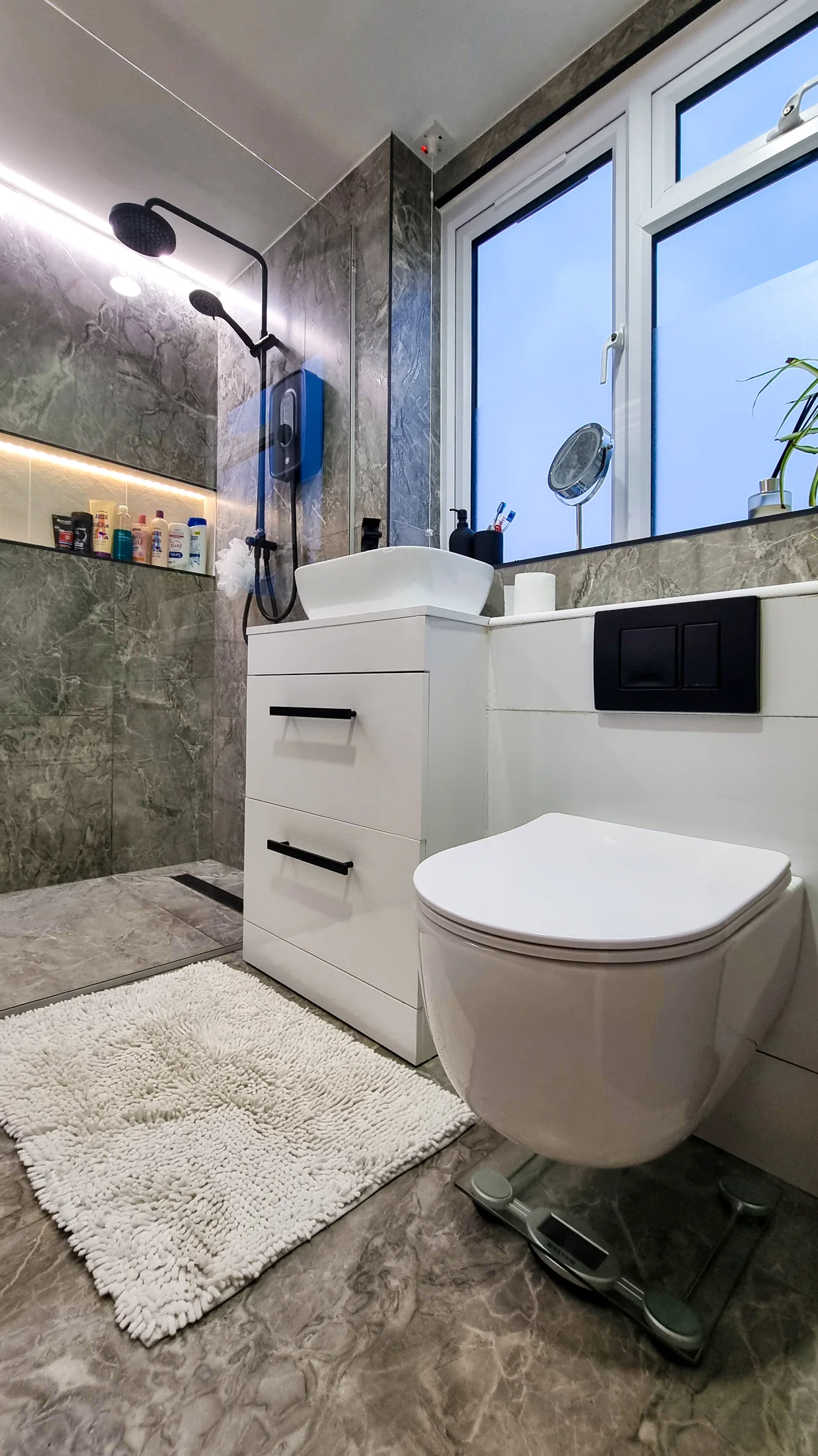 Wall-hung WC, white vanity and black fittings in the completed bathroom